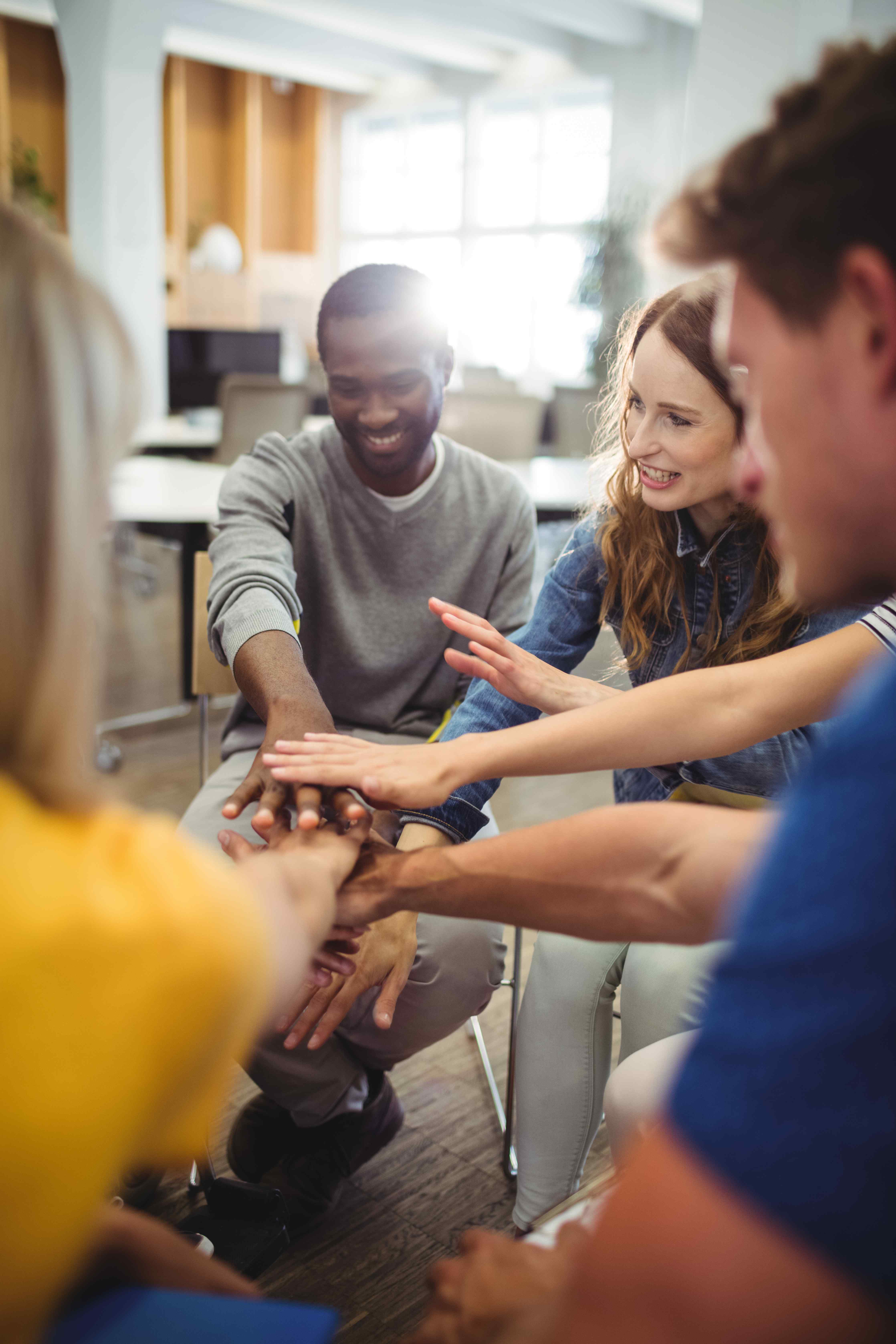 Diverse team joining hands together in an office